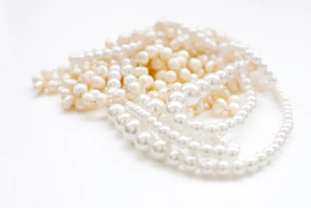 Luminous white pearls arranged in a refined still life on a soft neutral background, photographed for the Pearl Collection by Carabella by Cheryl