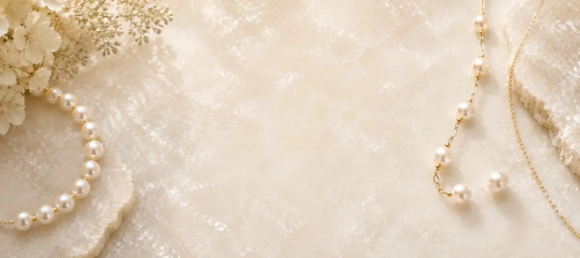Pearl necklace collection with luminous cream pearls and gold accents on softly textured ivory stone.