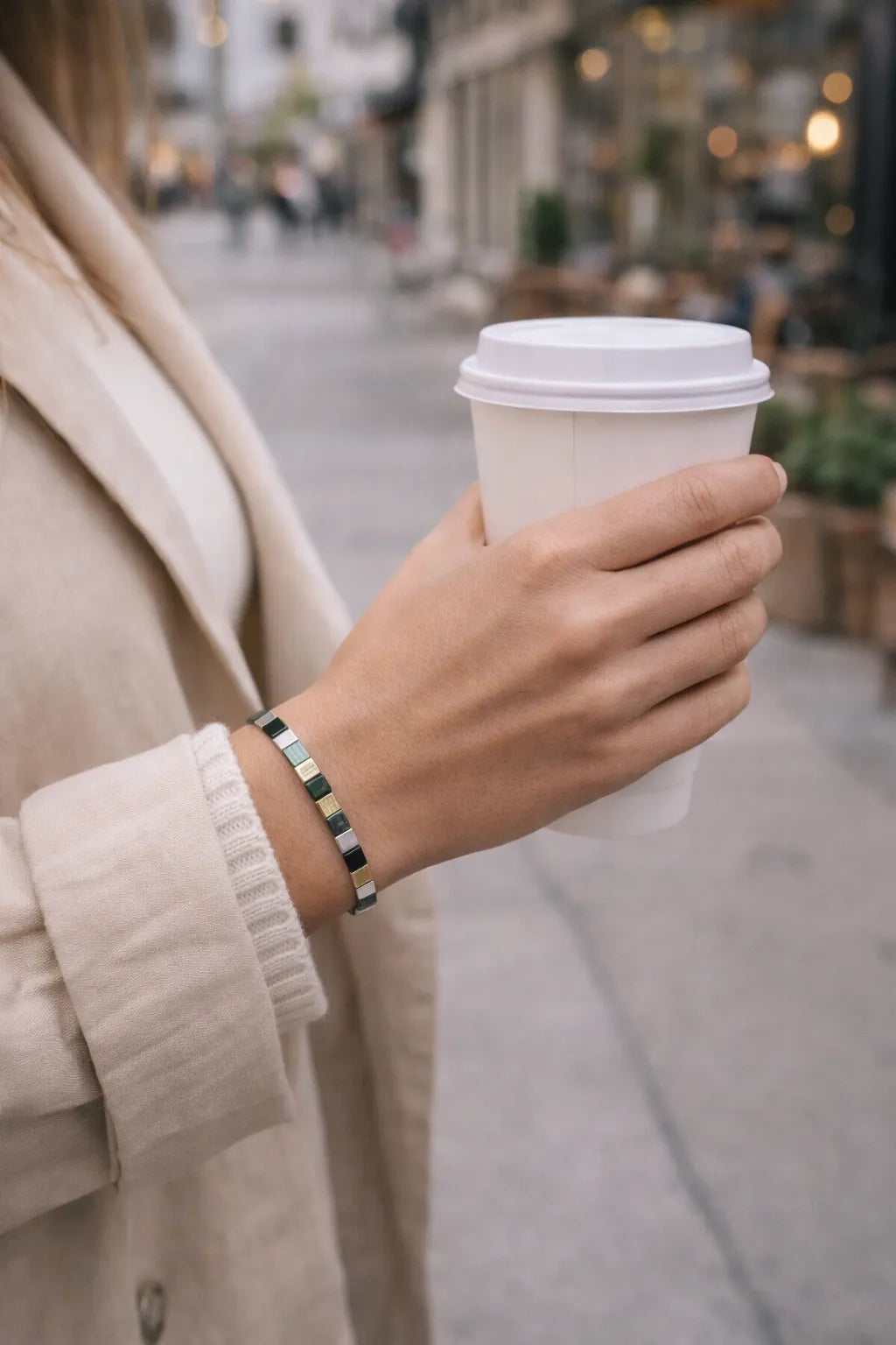 Ainsley Miyuki Tila bracelet worn casually with a neutral trench coat while holding a takeaway coffee in an urban setting