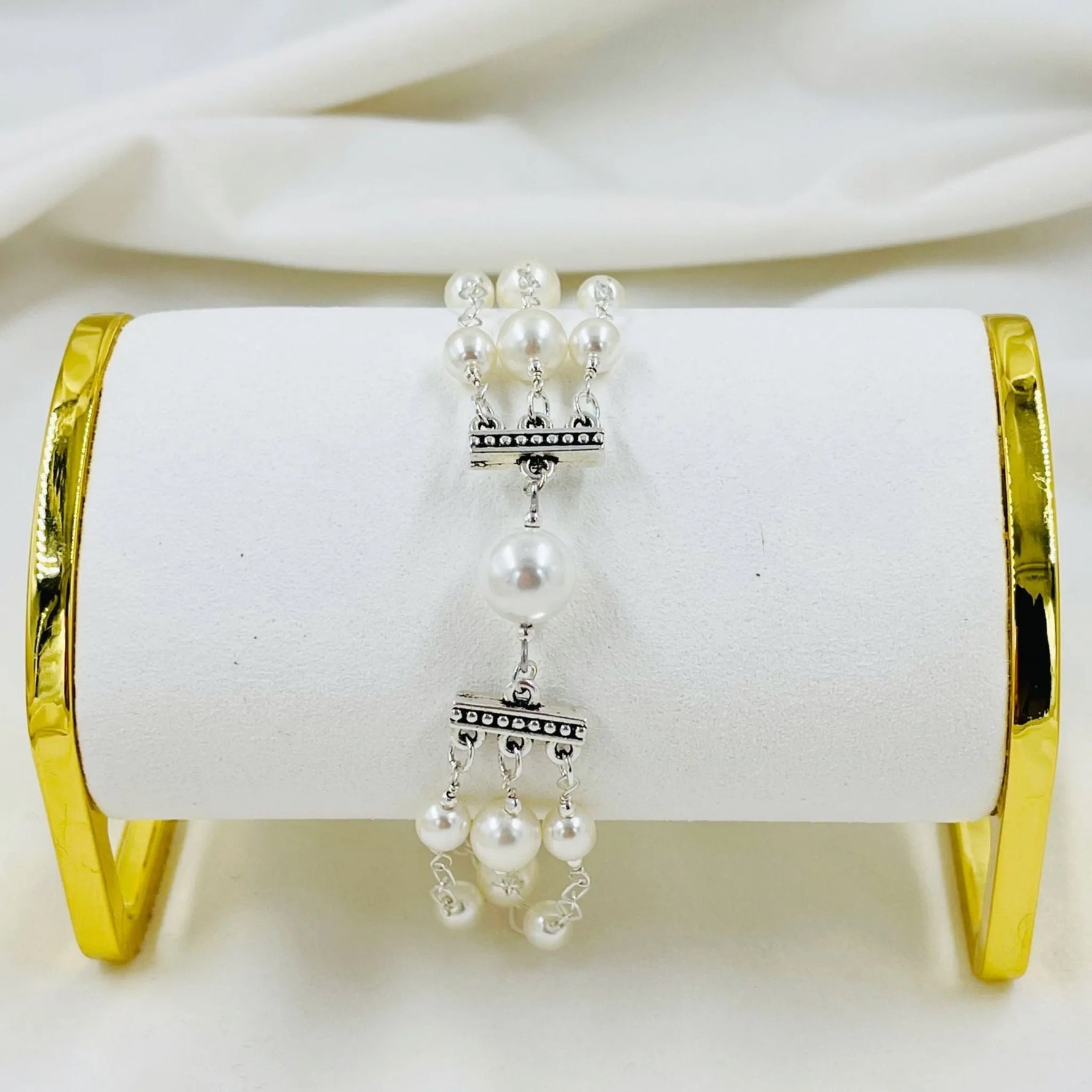 Elegant triple pearl bracelet with sterling silver accents displayed on jewelry stand