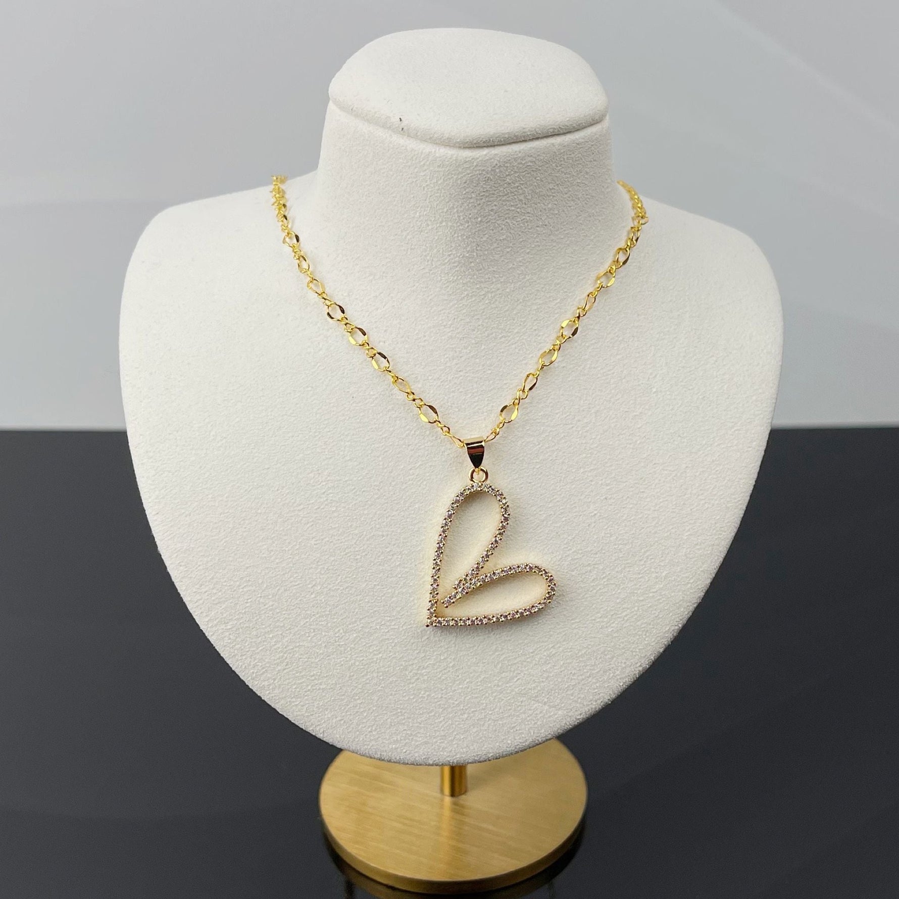 Angled view of Cara Gold Heart B Necklace featuring a pave heart pendant on gold chain