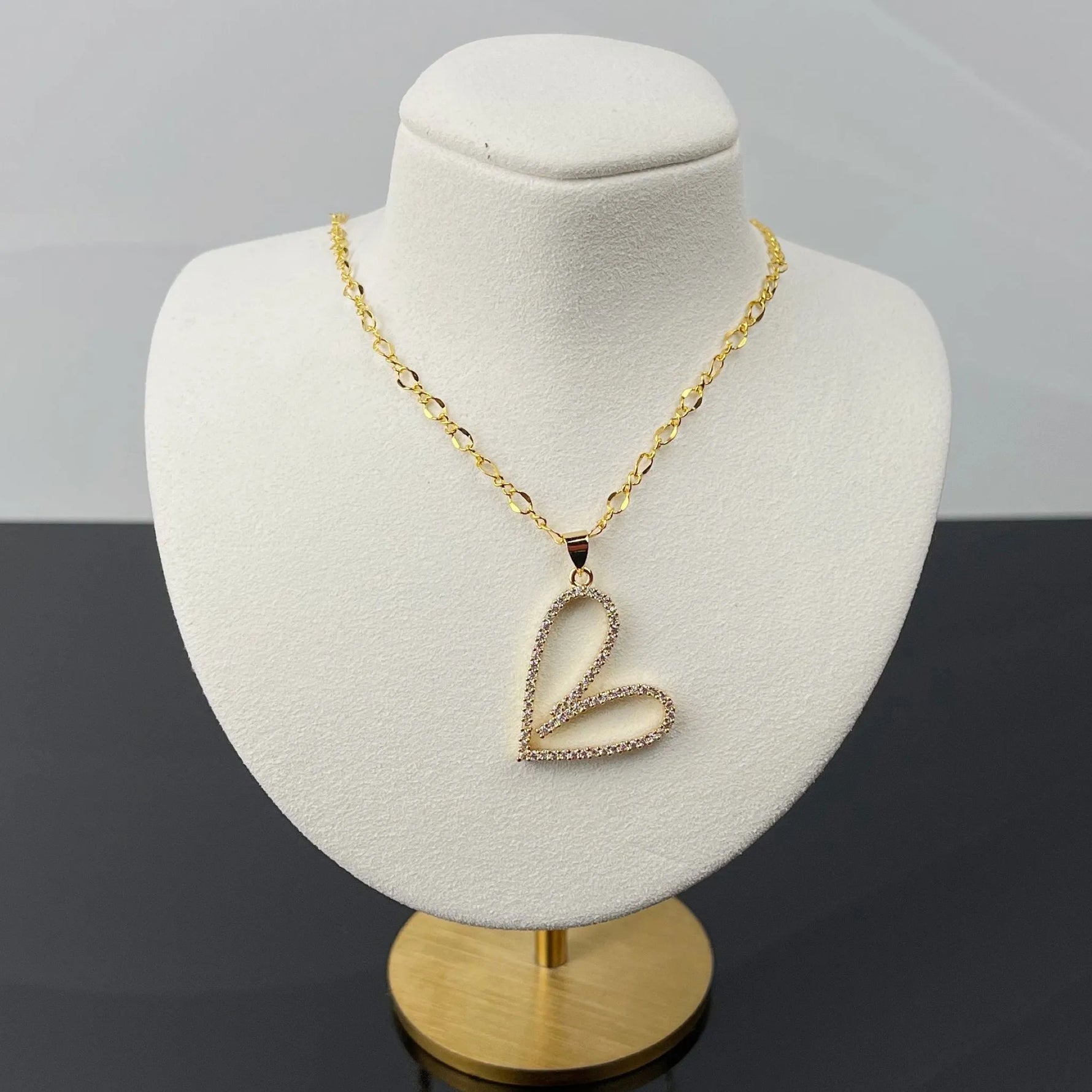 Angled view of Cara Gold Heart B Necklace featuring a pave heart pendant on gold chain