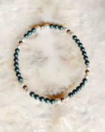 Kaia Pearl Stretch Bracelet featuring iridescent Tahitian Austrian crystal pearls, moonlight pearls, and gold accents styled on a soft natural stone background