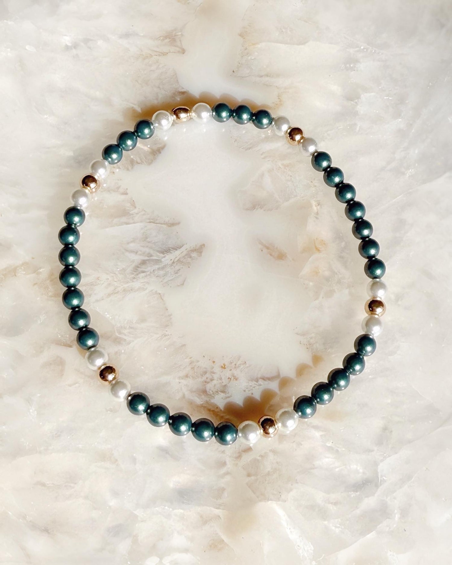 Kaia Pearl Stretch Bracelet featuring iridescent Tahitian Austrian crystal pearls, moonlight pearls, and gold accents styled on a soft natural stone background