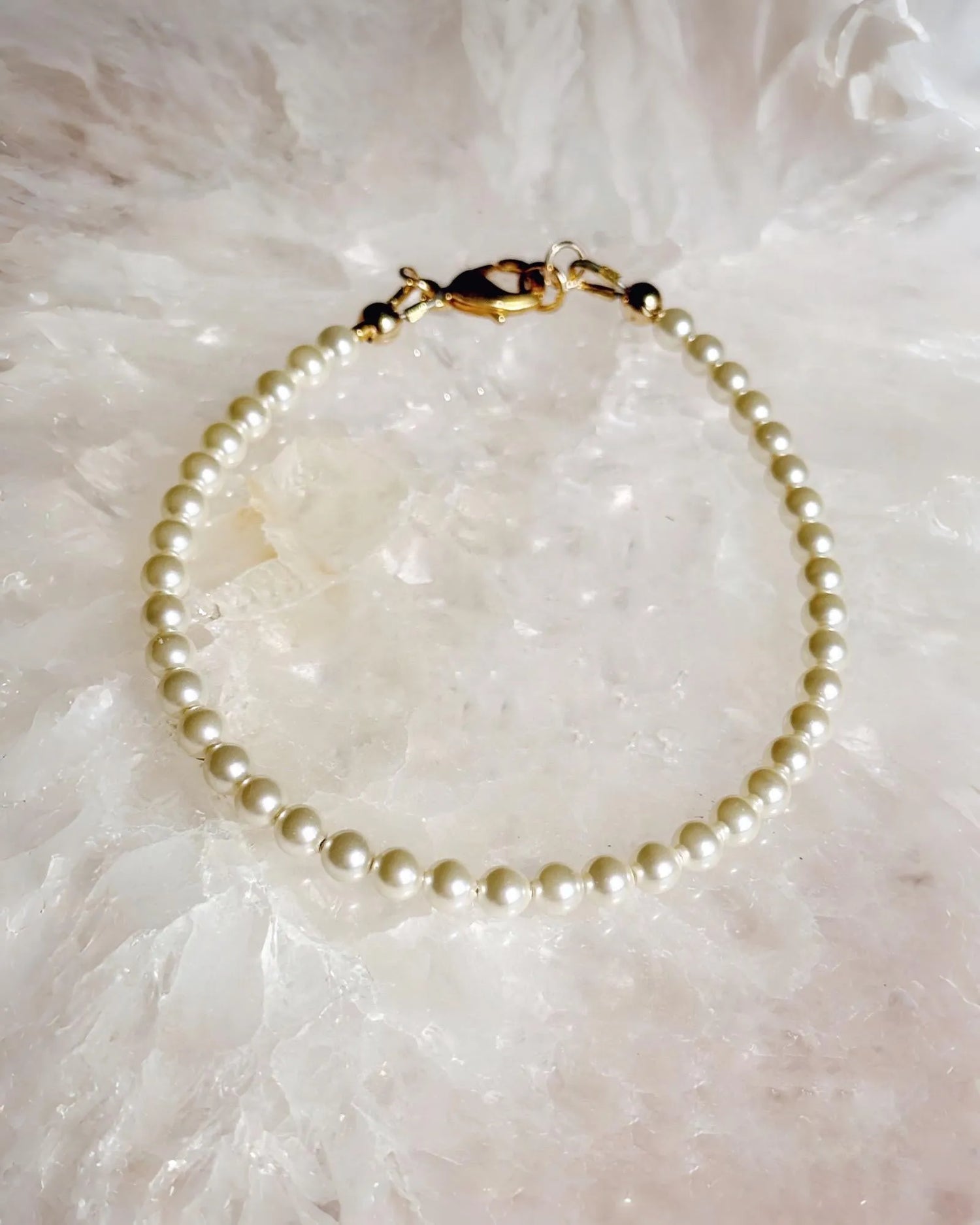 Leilani Cream Pearl Bracelet with delicate Austrian crystal pearls and a 14k gold clasp, photographed on a luminous stone background