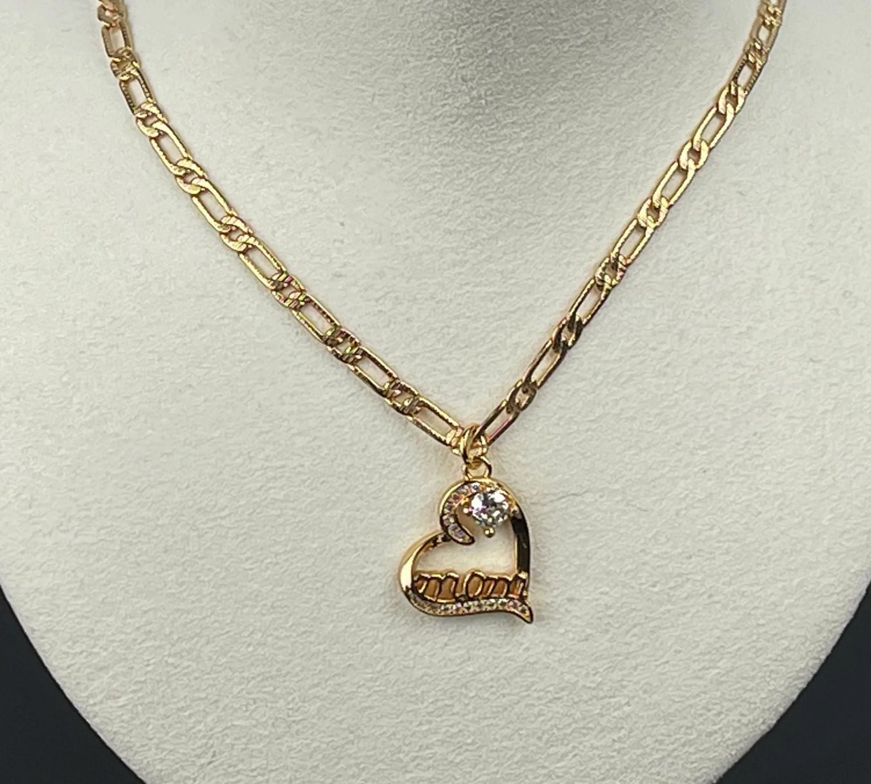 Eternal Love “Mom” heart necklace displayed on a neutral bust, highlighting the gold-plated chain and luminous cubic zirconia in Carabella by Cheryl’s signature understated luxury aesthetic.