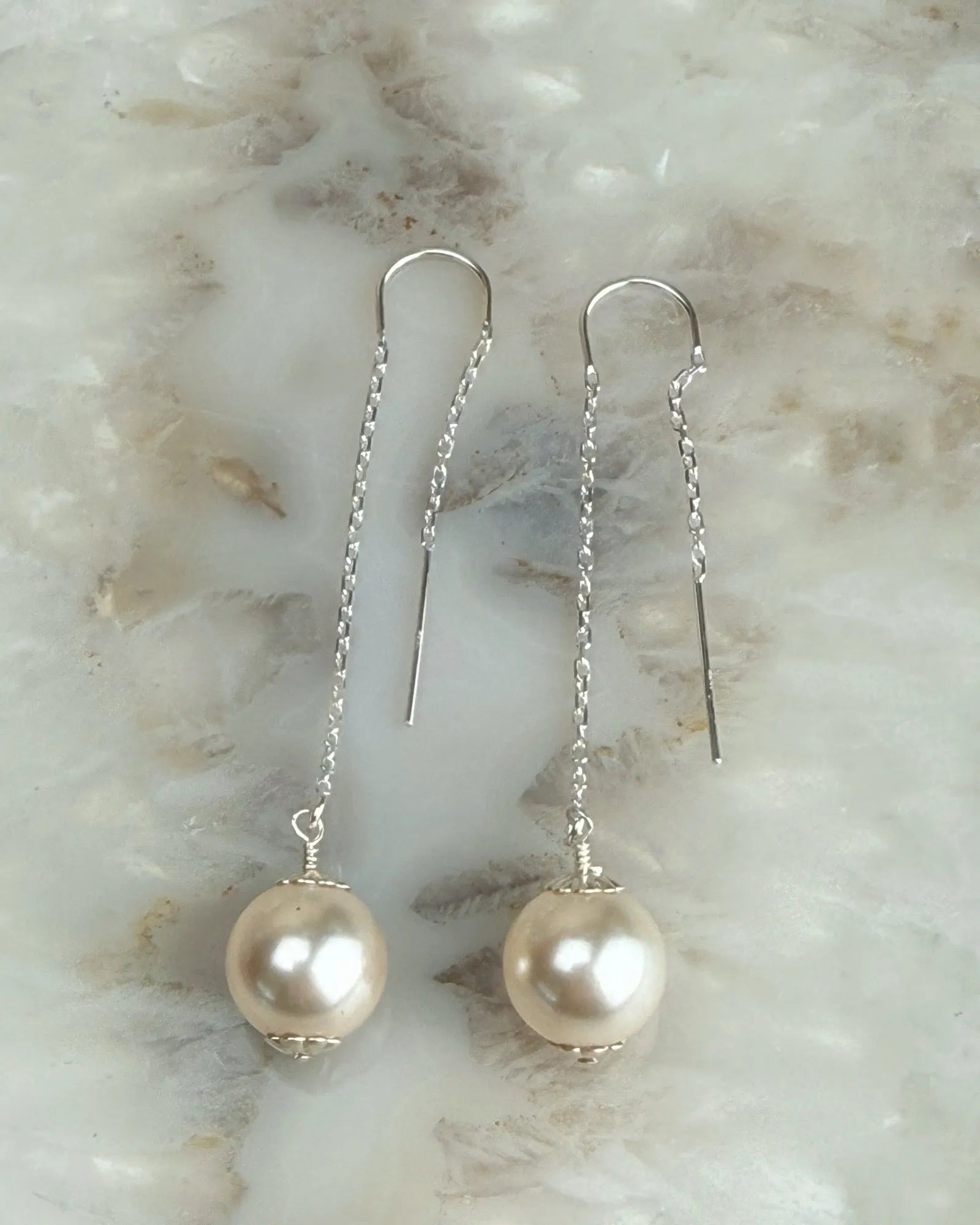 Emma Pearl Threader Earrings featuring European crystal pearls suspended from sterling silver threader chains on a soft stone background