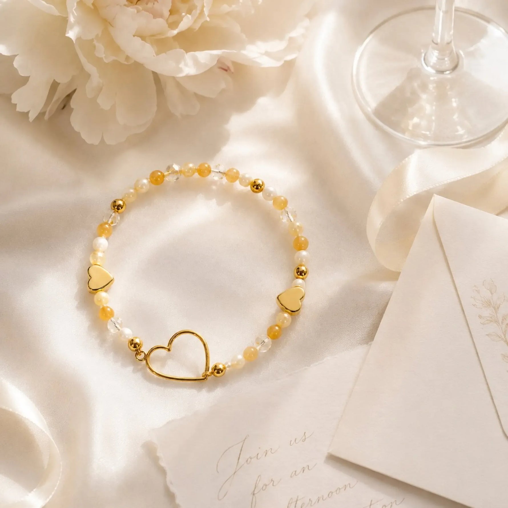 Editorial flat lay of the Harlow Gold Bracelet styled on ivory silk with elegant stationery, ribbon and floral accents.