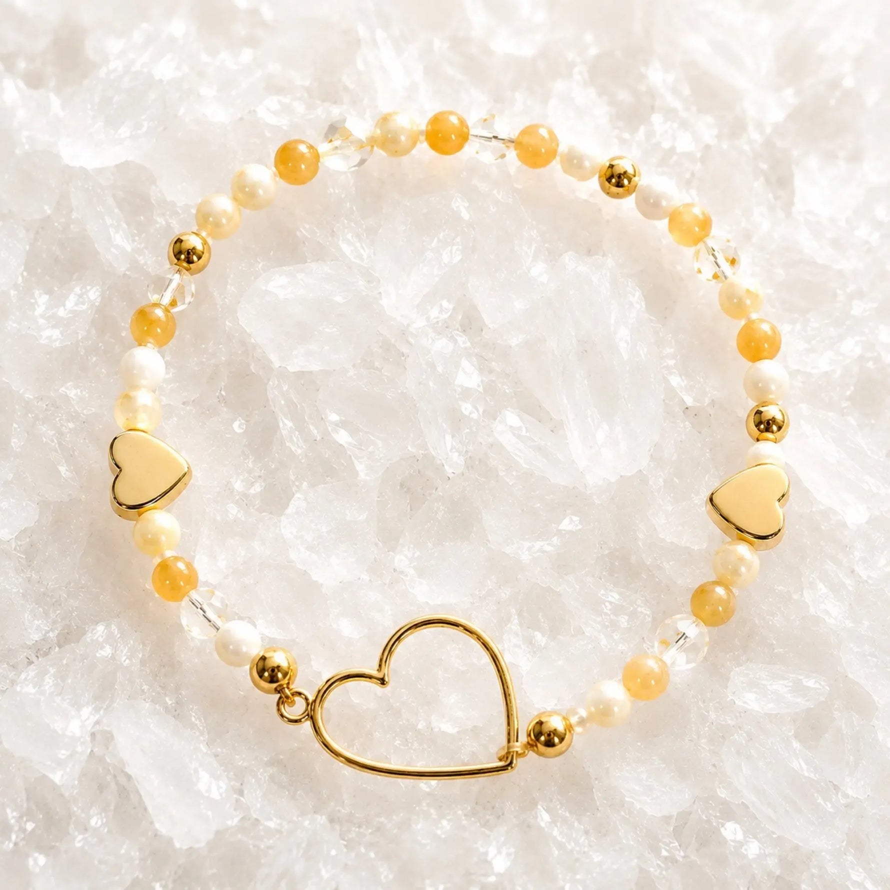 Harlow Gold Bracelet featuring honey opal gemstones, cream Swarovski® Crystal Pearls, crystal accents and gold heart details on a white quartz background.