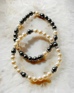 Juanita Pearl Stretch Bracelet stacked with the Jan Black Pearl Bracelet, highlighting contrast between cream pearls and dark grey pearls