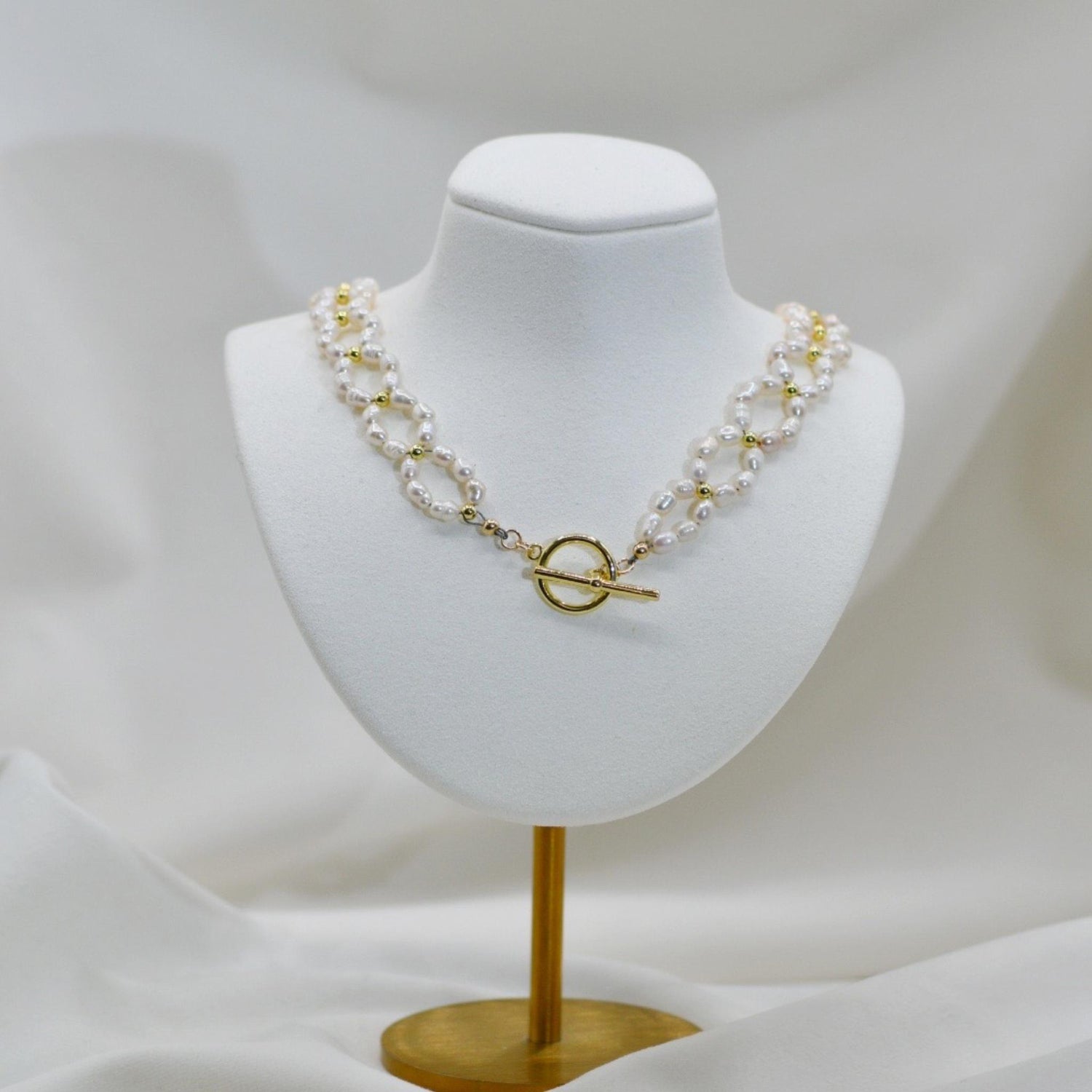 Kailani Freshwater Pearl Necklace displayed on jewelry bust, showcasing fluid pearl design with warm gold accents and classic sophistication