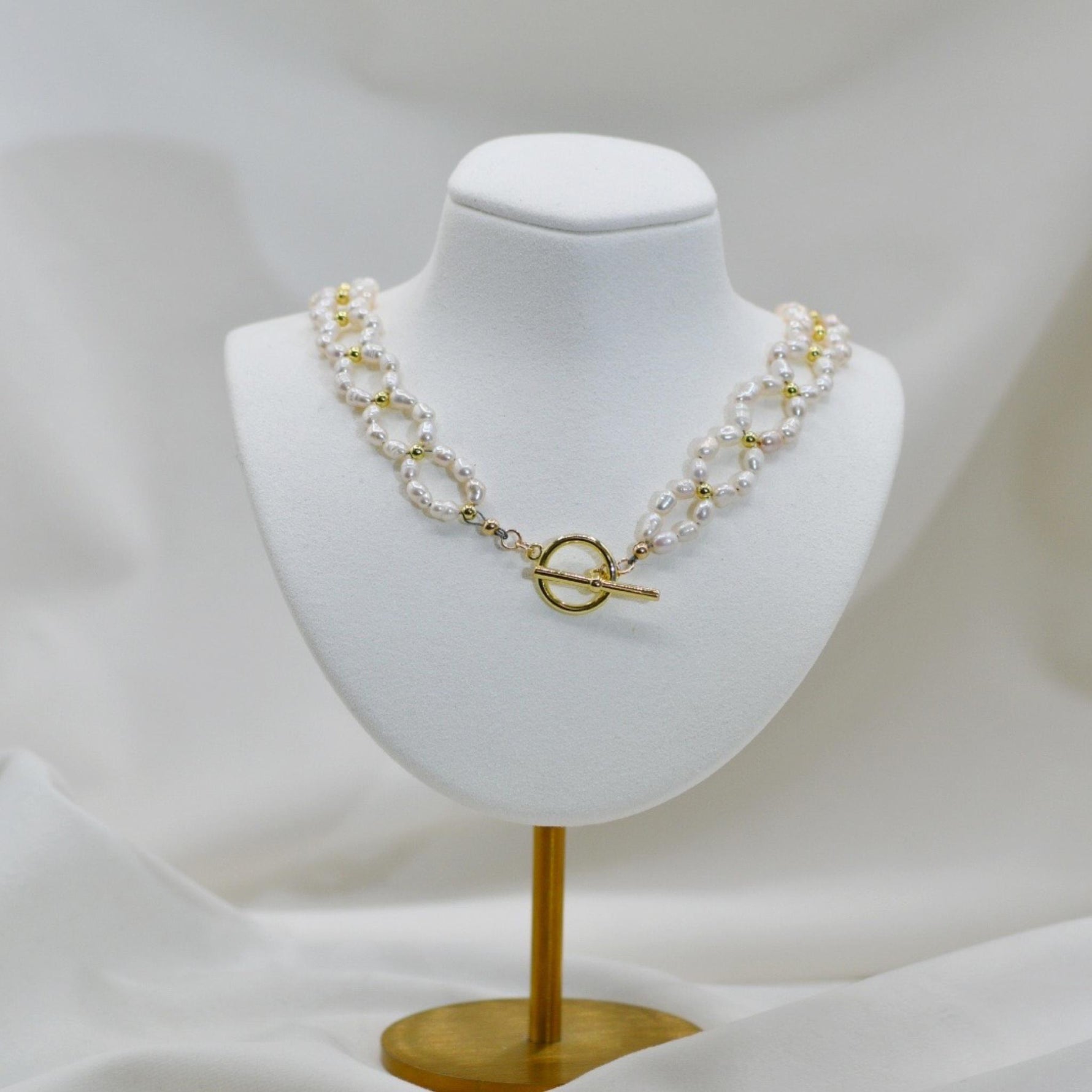 Kailani Freshwater Pearl Necklace displayed on jewelry bust, showcasing fluid pearl design with warm gold accents and classic sophistication