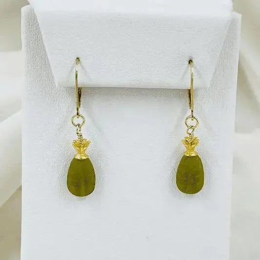 Layla Carved Jade Earrings displayed on a white jewelry stand, highlighting the sculpted jade drops and polished 14k gold detailing.