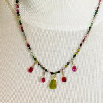 Model wearing the Layla Gemstone Necklace with rainbow tourmaline, ruby drops, and a carved jade leaf pendant styled over a neutral knit top.