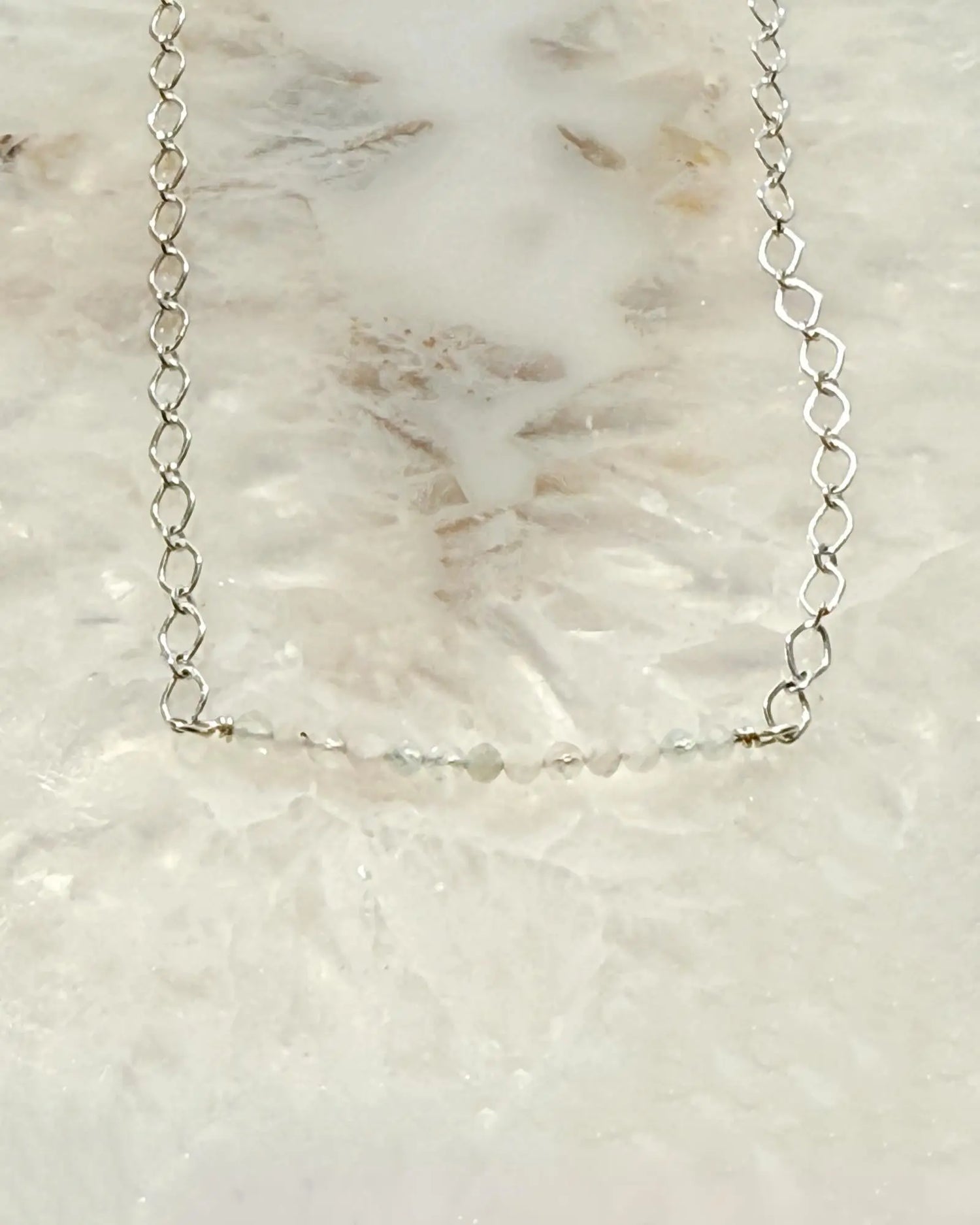 Flat lay of the Morganite Gemstone Bar Necklace featuring soft blush morganite gemstones set along a refined silver chain on a stone surface.