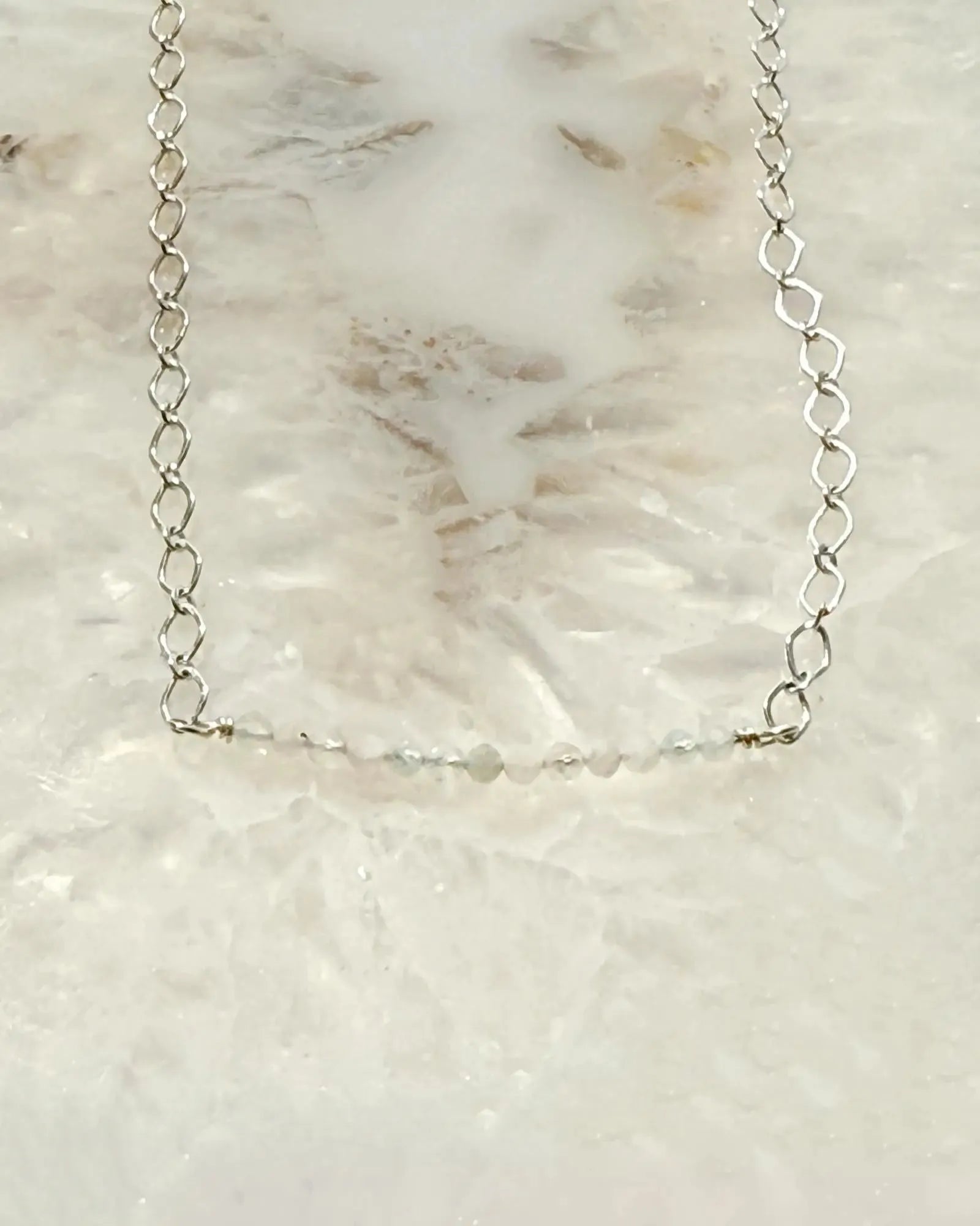 Flat lay of the Morganite Gemstone Bar Necklace featuring soft blush morganite gemstones set along a refined silver chain on a stone surface.