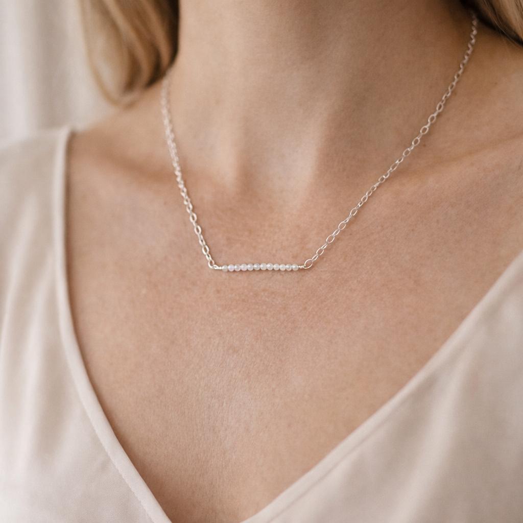 The Morganite Gemstone Bar Necklace worn at the neckline, showcasing soft pink morganite stones and an elegant silver chain for refined everyday styling.