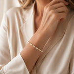 The Noelani Pearl Bracelet featuring Swarovski® Crystal Pearls and gold accents worn by an elegant woman in a luxury editorial portrait.