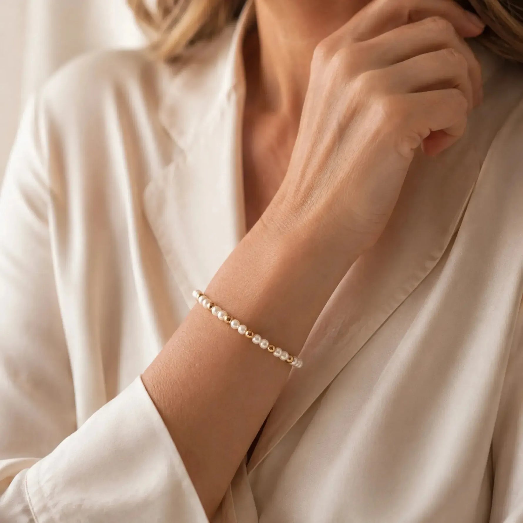 The Noelani Pearl Bracelet featuring Swarovski® Crystal Pearls and gold accents worn by an elegant woman in a luxury editorial portrait.