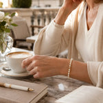 The Noelani Pearl Bracelet with Swarovski® Crystal Pearls and gold accents styled during a quiet morning coffee at a boutique hotel terrace.