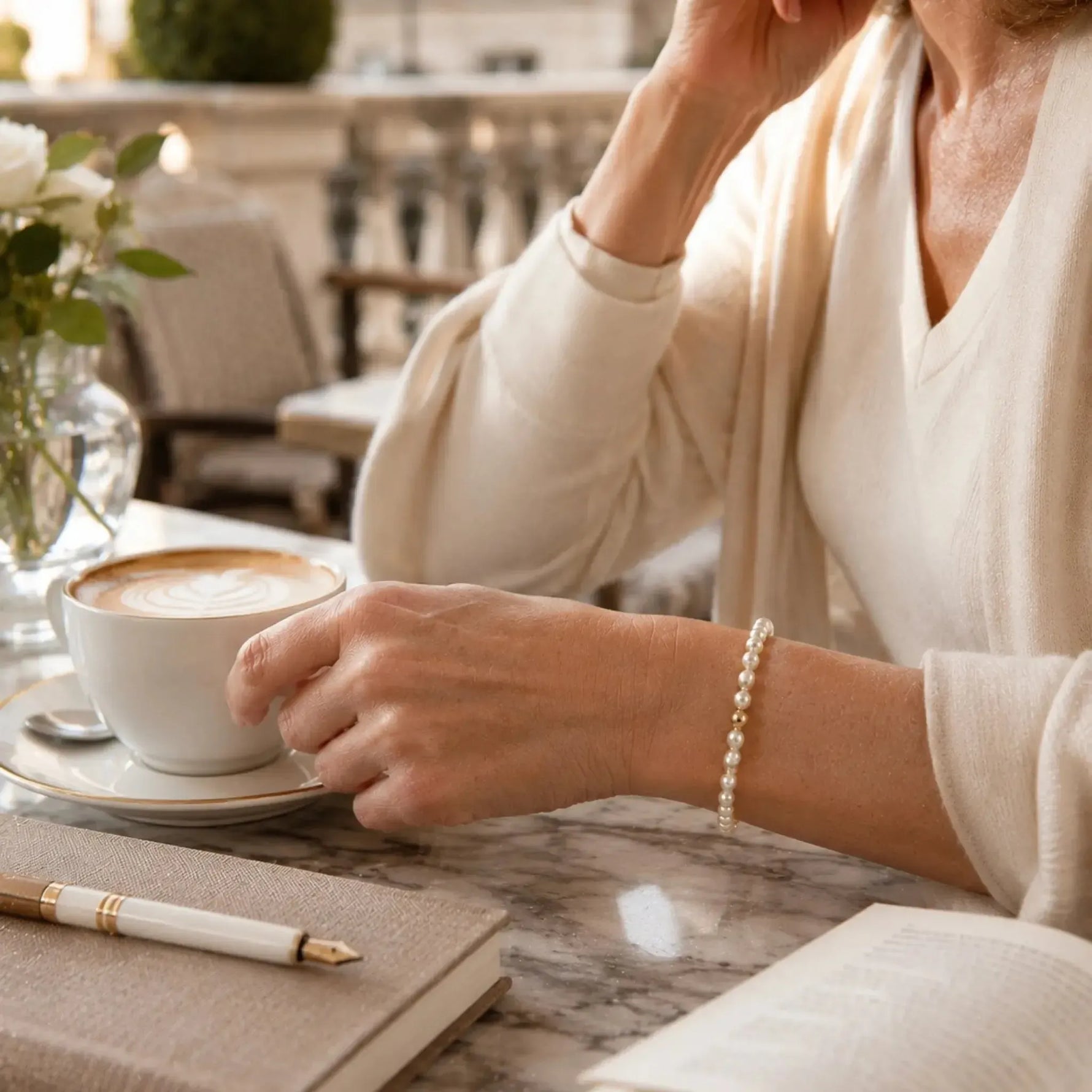 The Noelani Pearl Bracelet with Swarovski® Crystal Pearls and gold accents styled during a quiet morning coffee at a boutique hotel terrace.
