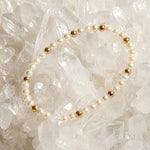 The Noelani Pearl Bracelet arranged atop luminous white quartz crystals, highlighting Swarovski® Crystal Pearls and gold accents.