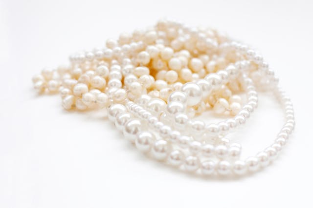 Luminous white pearls arranged in a refined still life on a soft neutral background, photographed for the Pearl Collection by Carabella by Cheryl