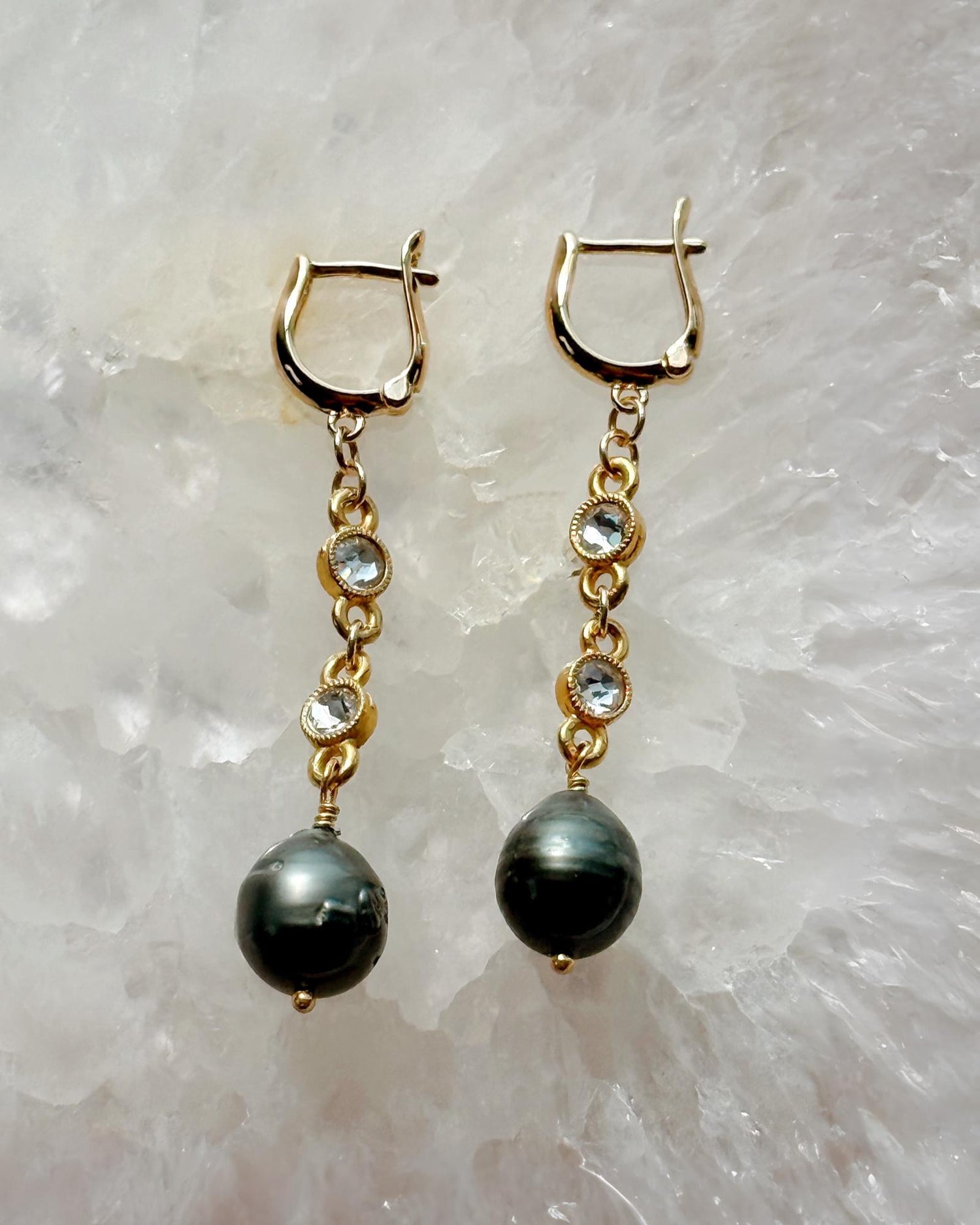 Angled detail view of Tahitian South Sea black pearl earrings featuring gold findings and sparkling crystal accents by Carabella by Cheryl.
