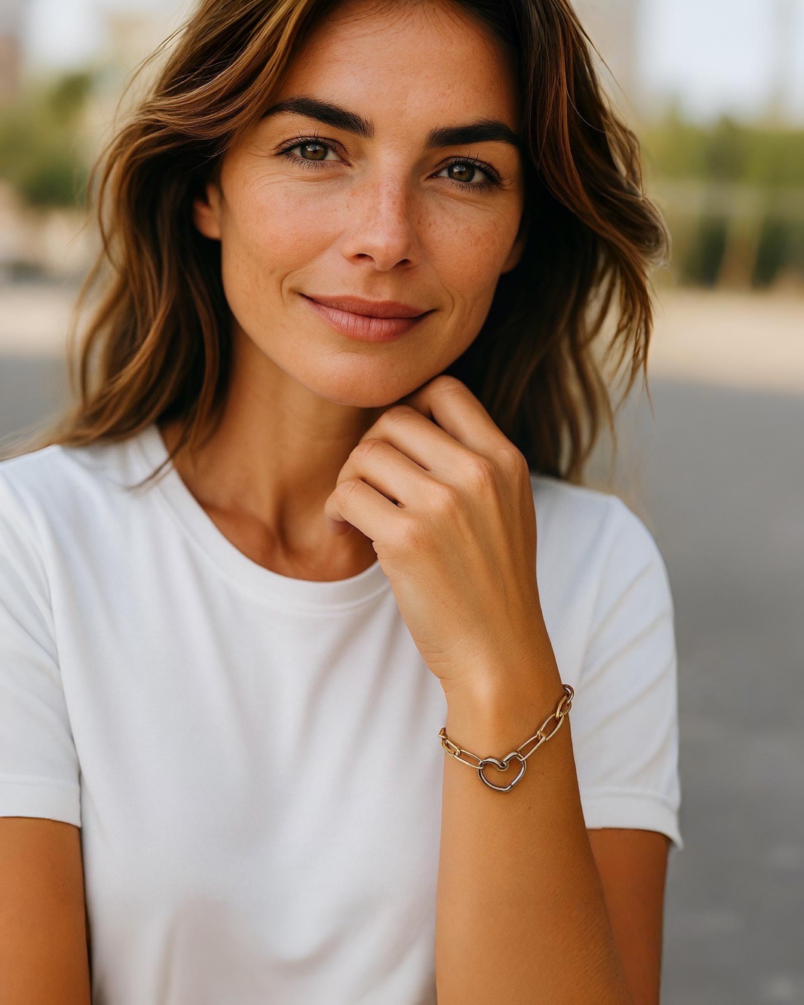 Model wearing gold paperclip bracelet with silver heart clasp elegant mixed metal jewelry