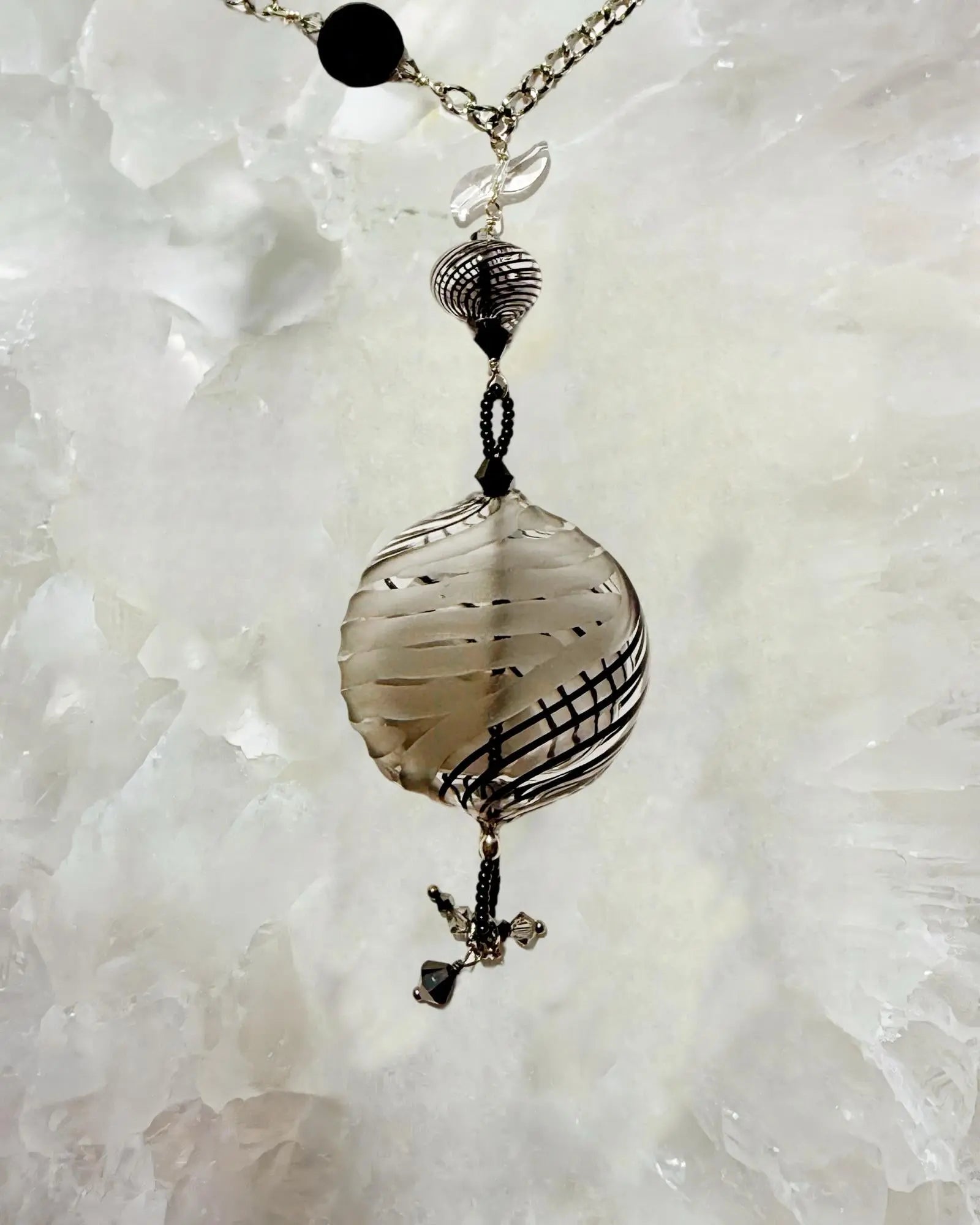 Flat lay of the Venezia Murano Glass Statement Necklace highlighting the Murano glass focal bead, European crystal accents, and stainless steel chain on a white stone background.