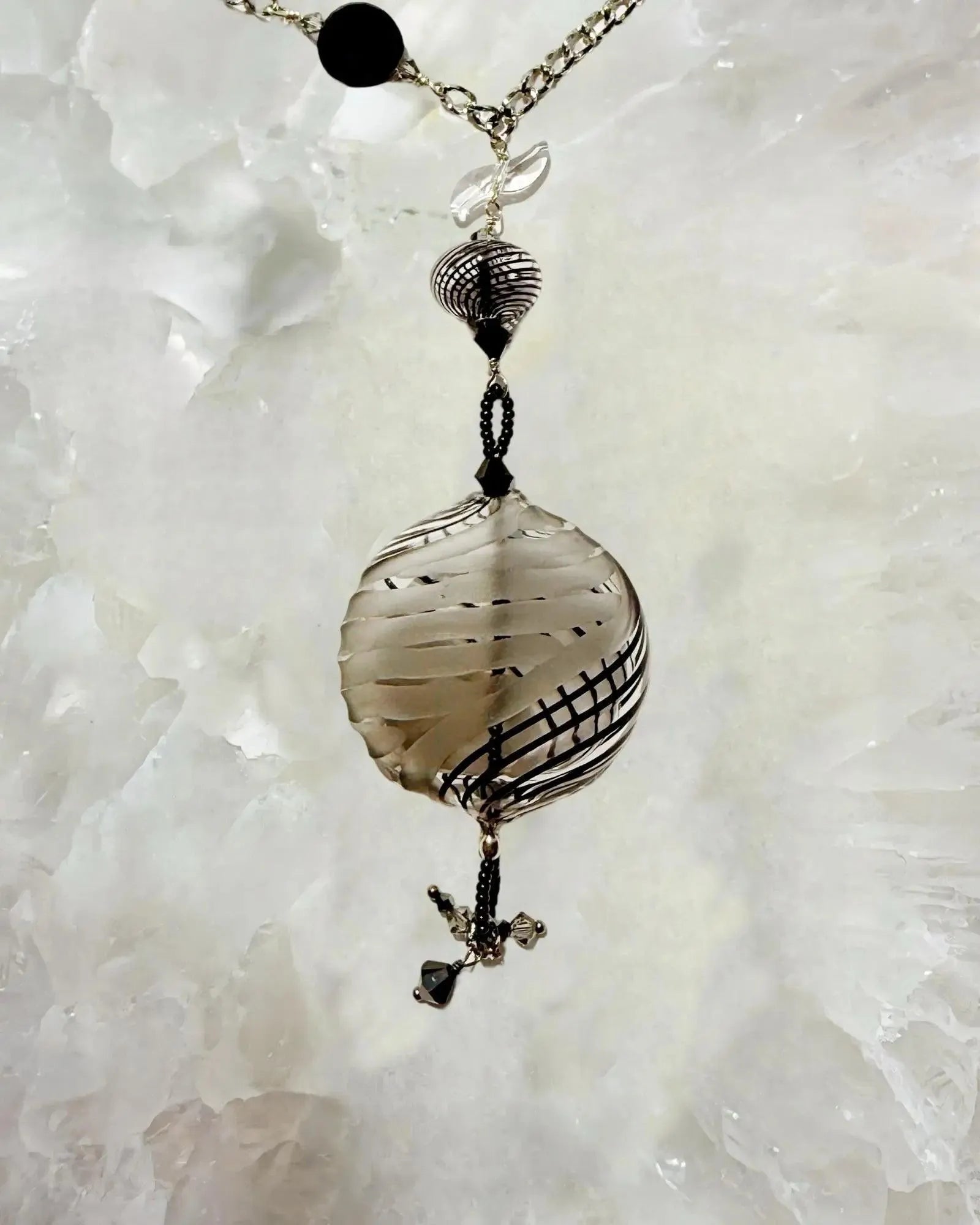 Flat lay of the Venezia Murano Glass Statement Necklace highlighting the Murano glass focal bead, European crystal accents, and stainless steel chain on a white stone background.