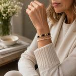 Ainsley Miyuki Tila Bracelet layered with the Noelani Swarovski® Crystal Pearl Bracelet on the wrist of a woman wearing an ivory cashmere sweater, showcasing effortless everyday styling and quiet luxury.