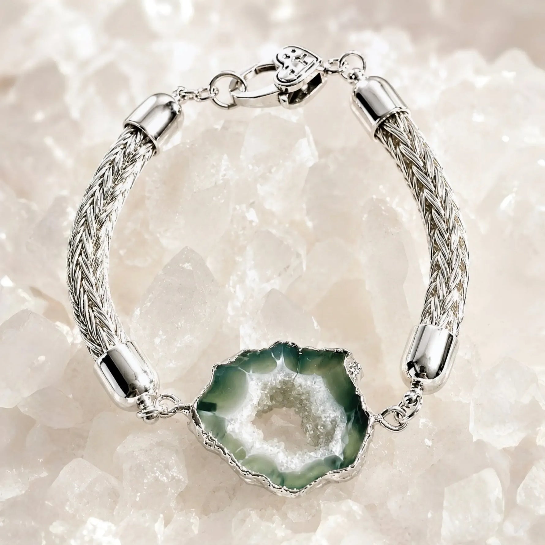 Ava handwoven .999 fine silver bracelet with natural green agate druzy centre displayed on white quartz, showcasing artisan silver craftsmanship and organic gemstone beauty.