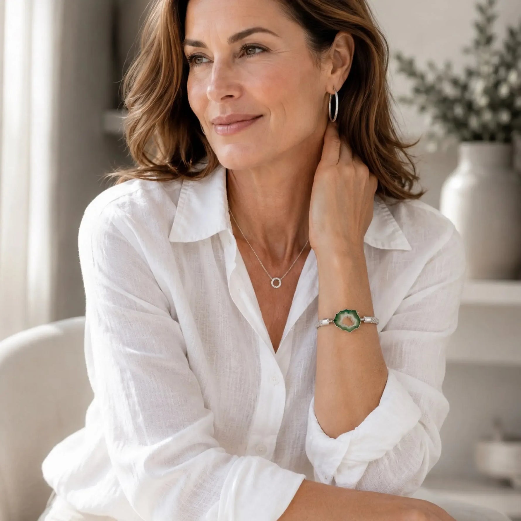 Elegant woman wearing the Ava handwoven .999 fine silver bracelet with natural green agate druzy, styled with a white linen blouse and quiet luxury accessories.