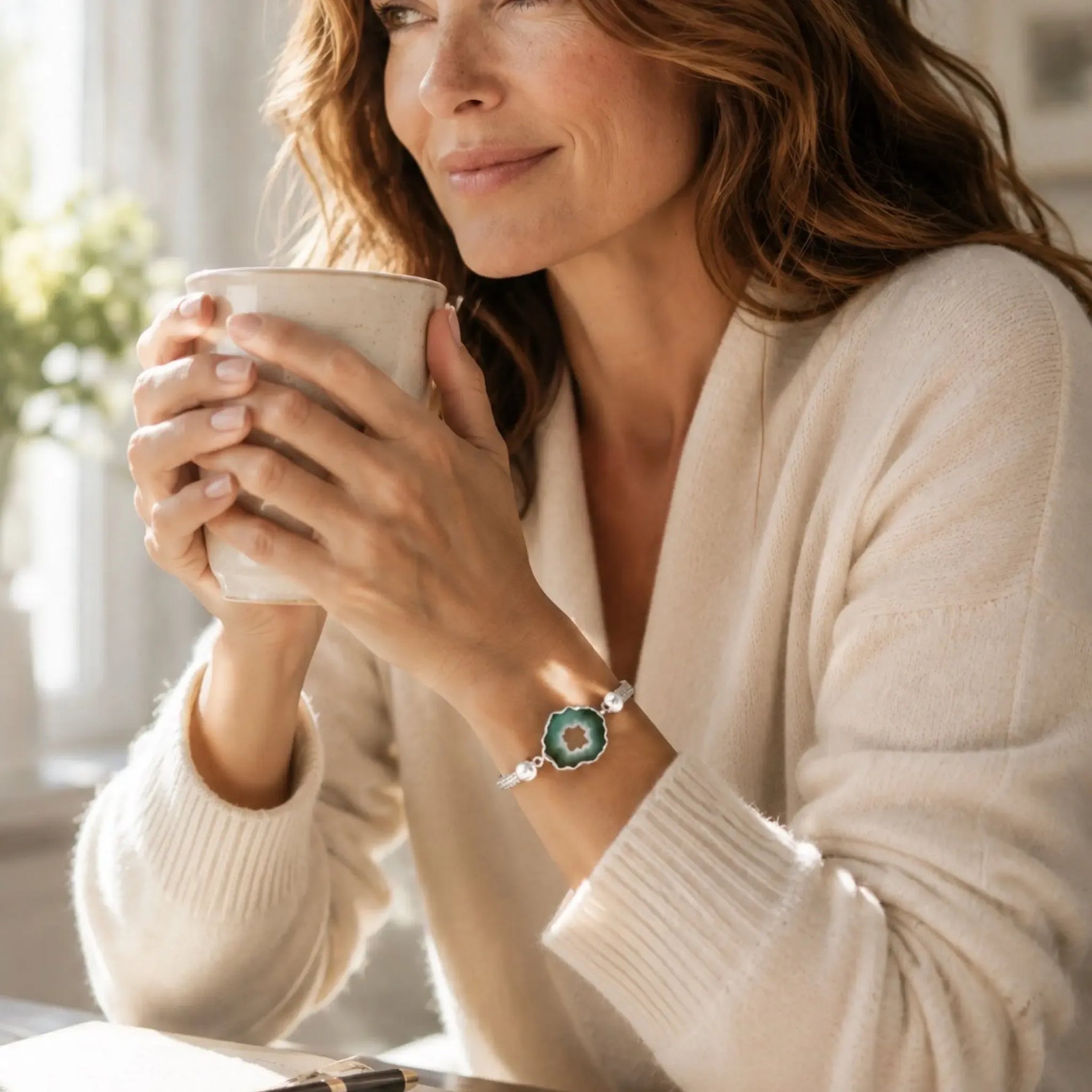 Ava handwoven .999 fine silver bracelet with natural green agate druzy worn during a relaxed morning coffee, styled with a cream cashmere sweater in warm natural light.