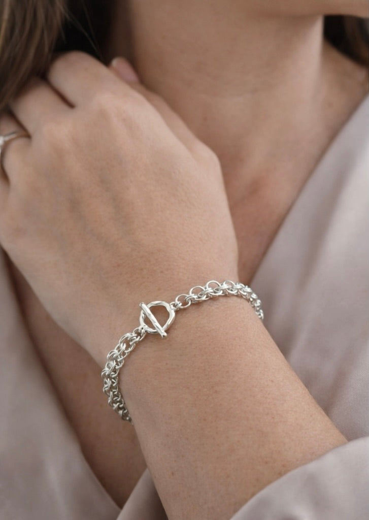 Avalon Celtic Helm chainmaille bracelet in sterling silver worn on the wrist, showcasing sculptural links and quiet luxury in a refined, neutral setting.