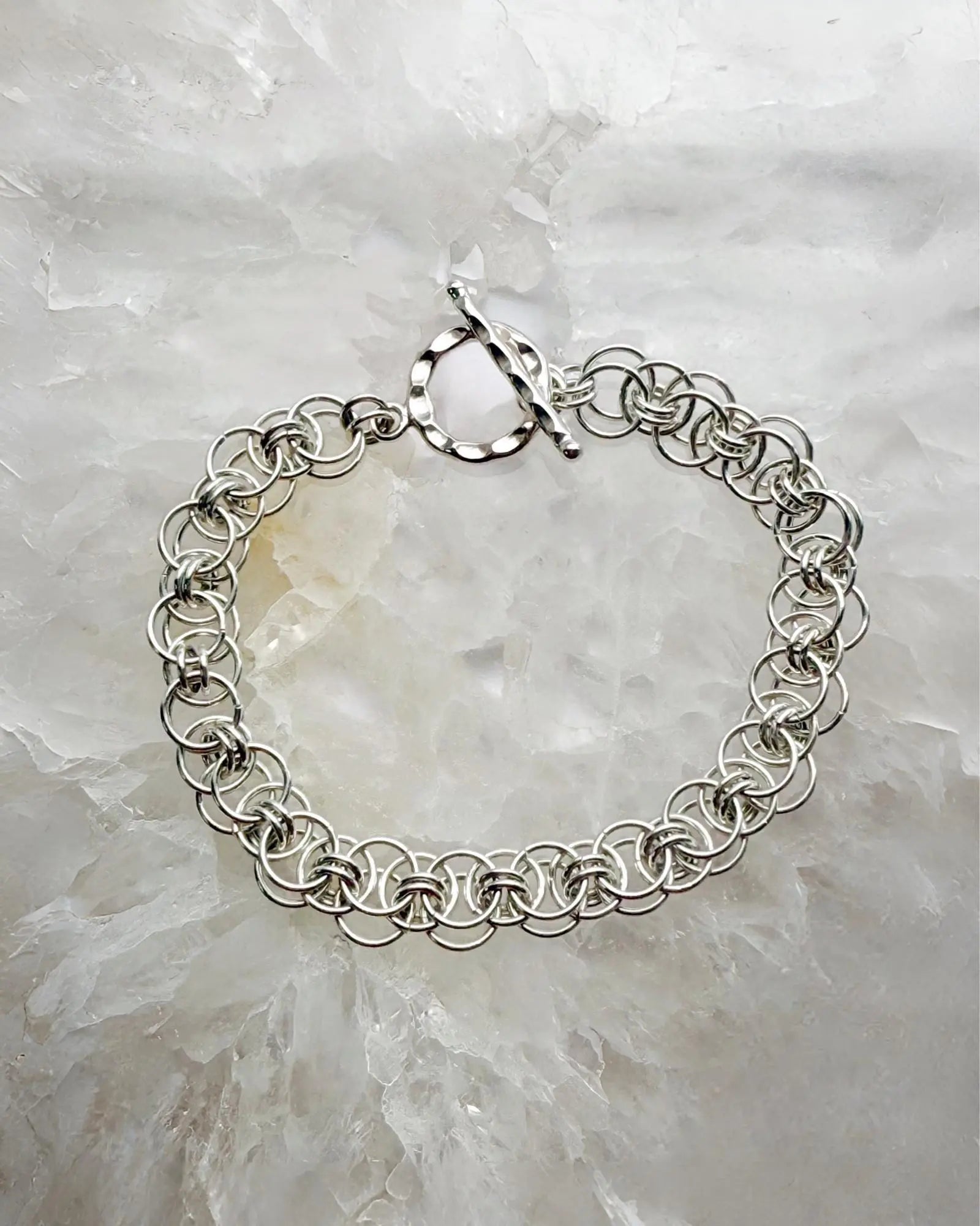 Avalon sterling silver bracelet featuring an intricate Celtic Helm chainmaille weave, styled on a luminous stone backdrop with refined elegance.
