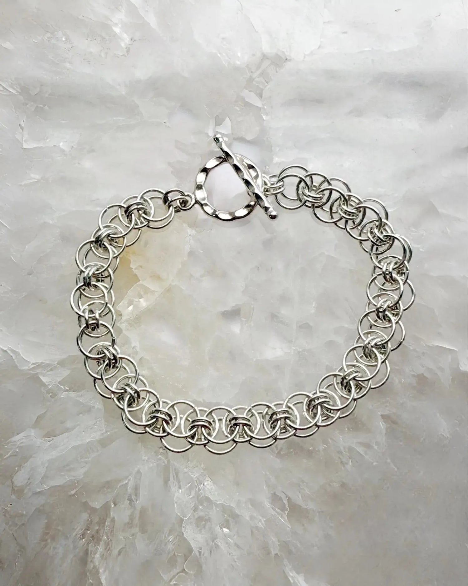 Avalon sterling silver bracelet featuring an intricate Celtic Helm chainmaille weave, styled on a luminous stone backdrop with refined elegance.