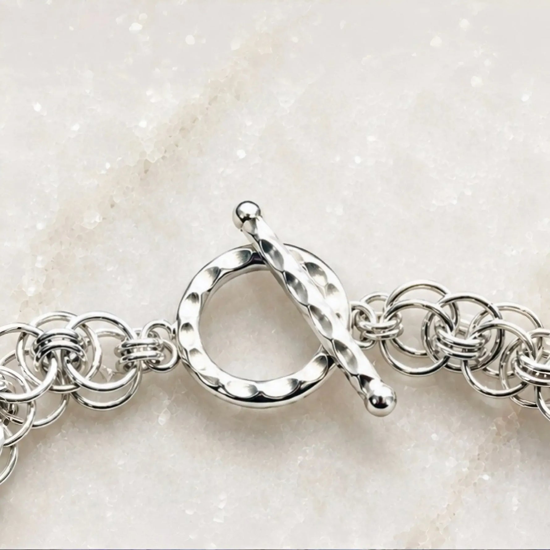Macro view of the Avalon bracelet’s hammered sterling silver toggle clasp and adjoining handwoven Celtic helm links.