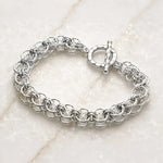 Angled view of the Avalon sterling silver Celtic helm bracelet highlighting the dimensional handwoven rings and hammered toggle clasp.
