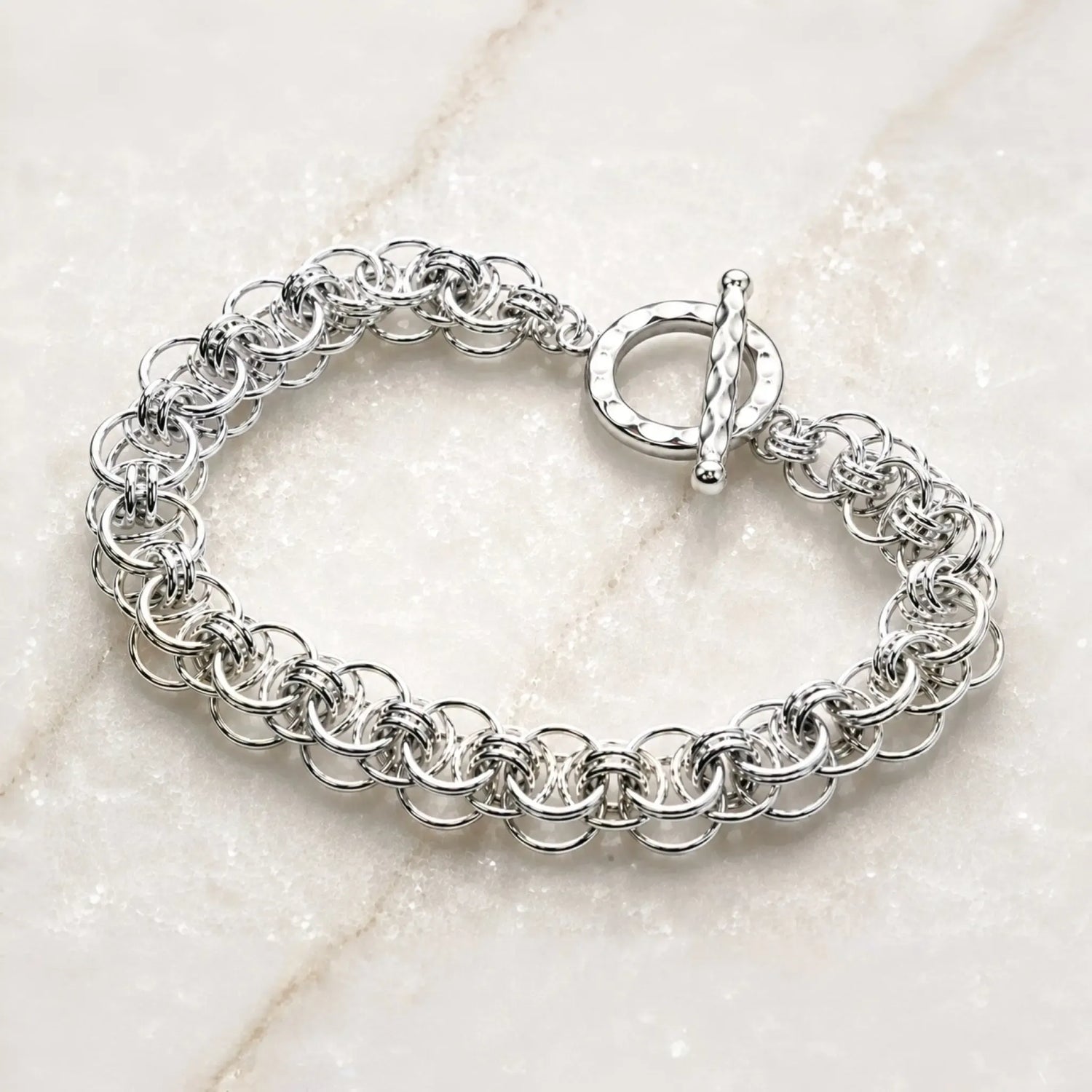 Angled view of the Avalon sterling silver Celtic helm bracelet highlighting the dimensional handwoven rings and hammered toggle clasp.