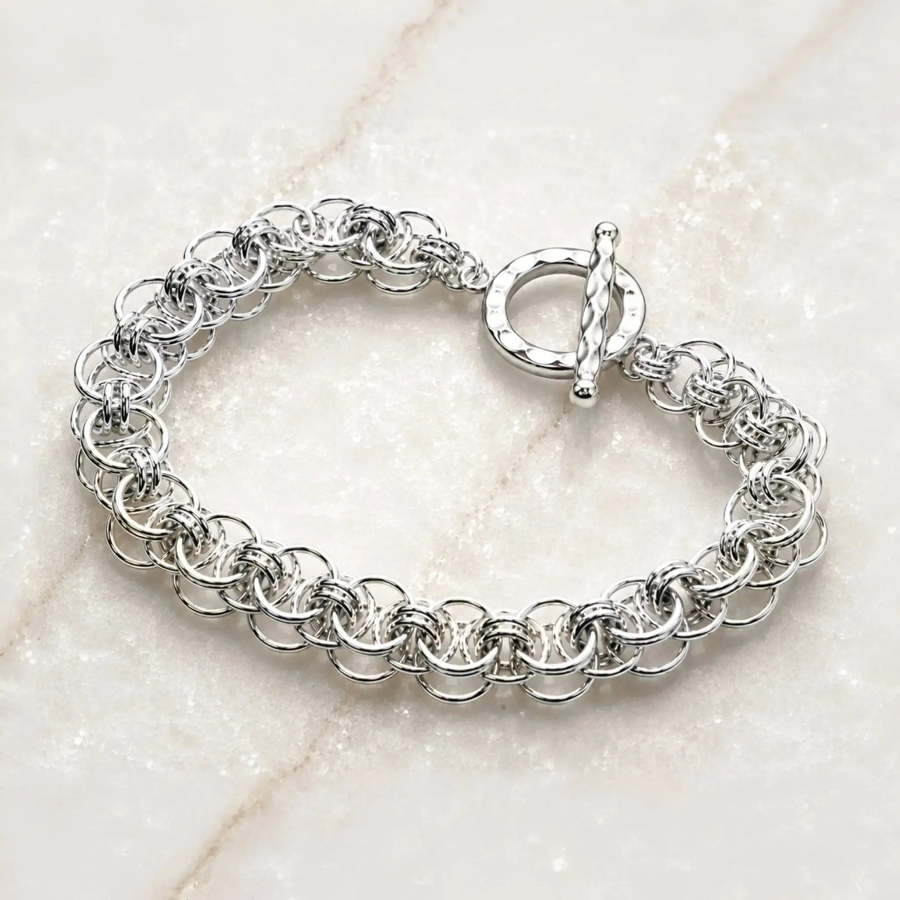 Angled view of the Avalon sterling silver Celtic helm bracelet highlighting the dimensional handwoven rings and hammered toggle clasp.