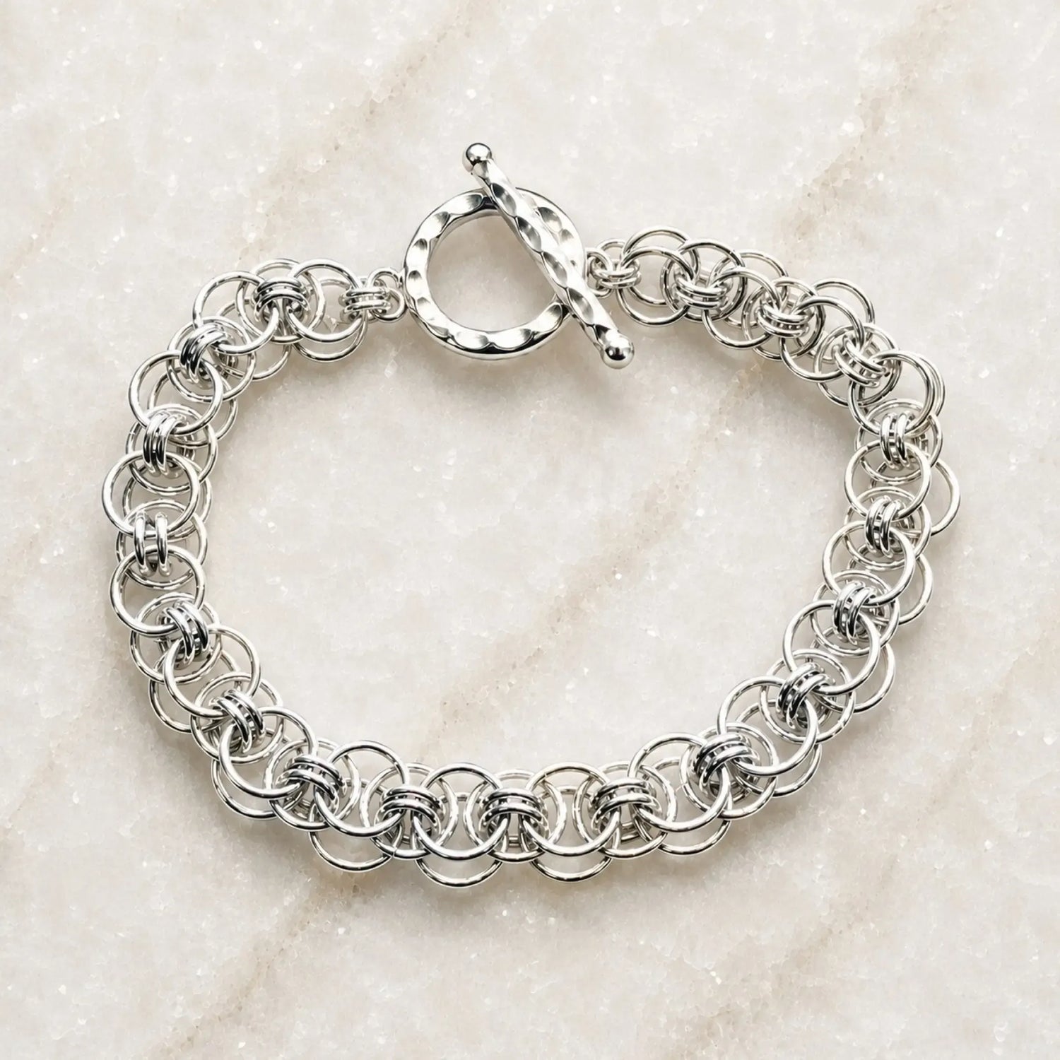Avalon sterling silver bracelet with an intricate handwoven Celtic helm chainmaille design and hammered toggle clasp on white quartz.
