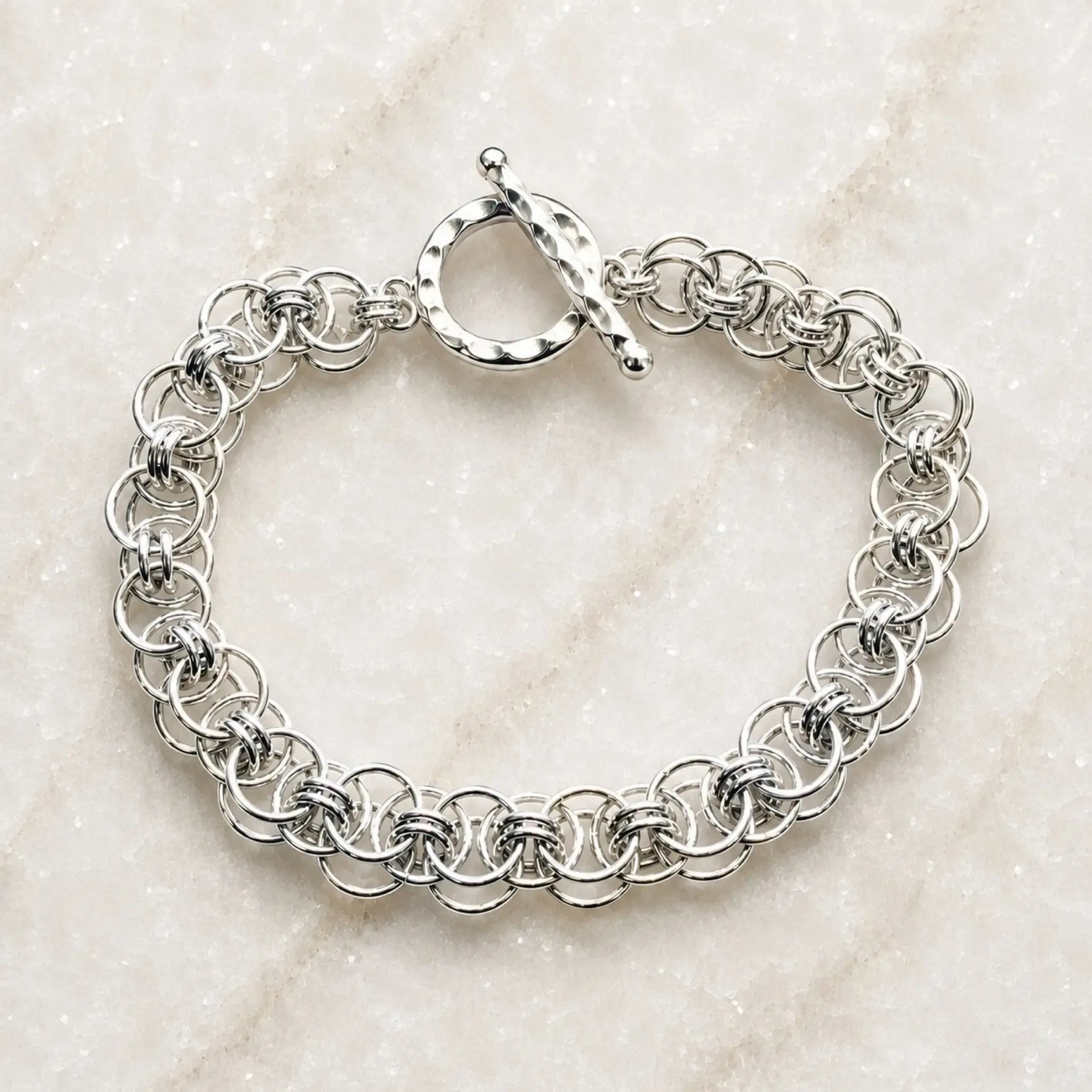 Avalon sterling silver bracelet with an intricate handwoven Celtic helm chainmaille design and hammered toggle clasp on white quartz.