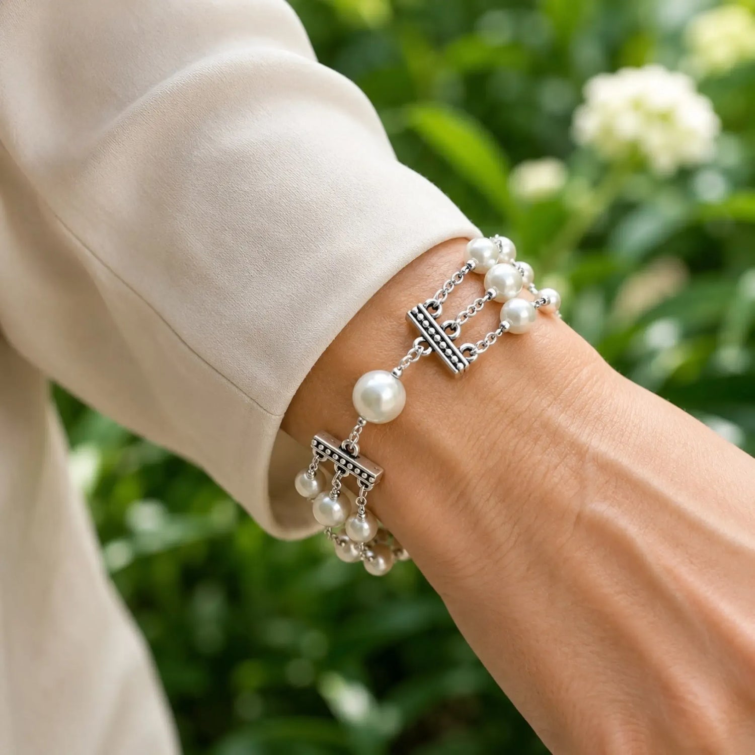Close-up of the Calla triple strand Swarovski® Crystal Pearl bracelet worn with an ivory silk blouse, showing natural fit and elegant proportions.