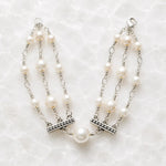 Calla handcrafted triple strand Swarovski® Crystal Pearl bracelet with sterling silver accents on a white quartz background.