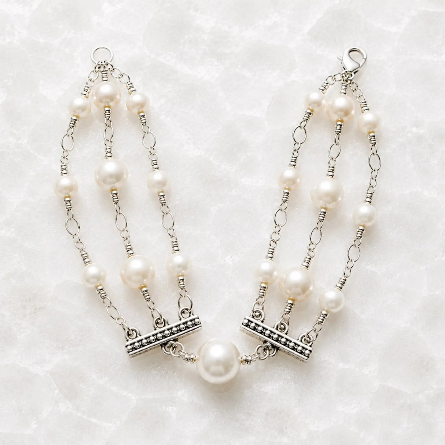 Calla handcrafted triple strand Swarovski® Crystal Pearl bracelet with sterling silver accents on a white quartz background.