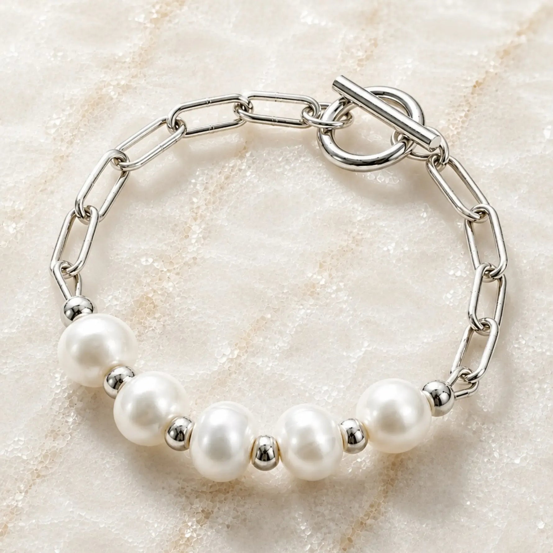 Angled view of the Callie freshwater pearl bracelet featuring 9–10 mm freshwater pearls, polished silver paperclip chain and toggle clasp.