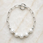 Callie freshwater pearl bracelet handcrafted in Canada with 9–10 mm freshwater pearls, silver paperclip chain and toggle clasp on white quartz background.
