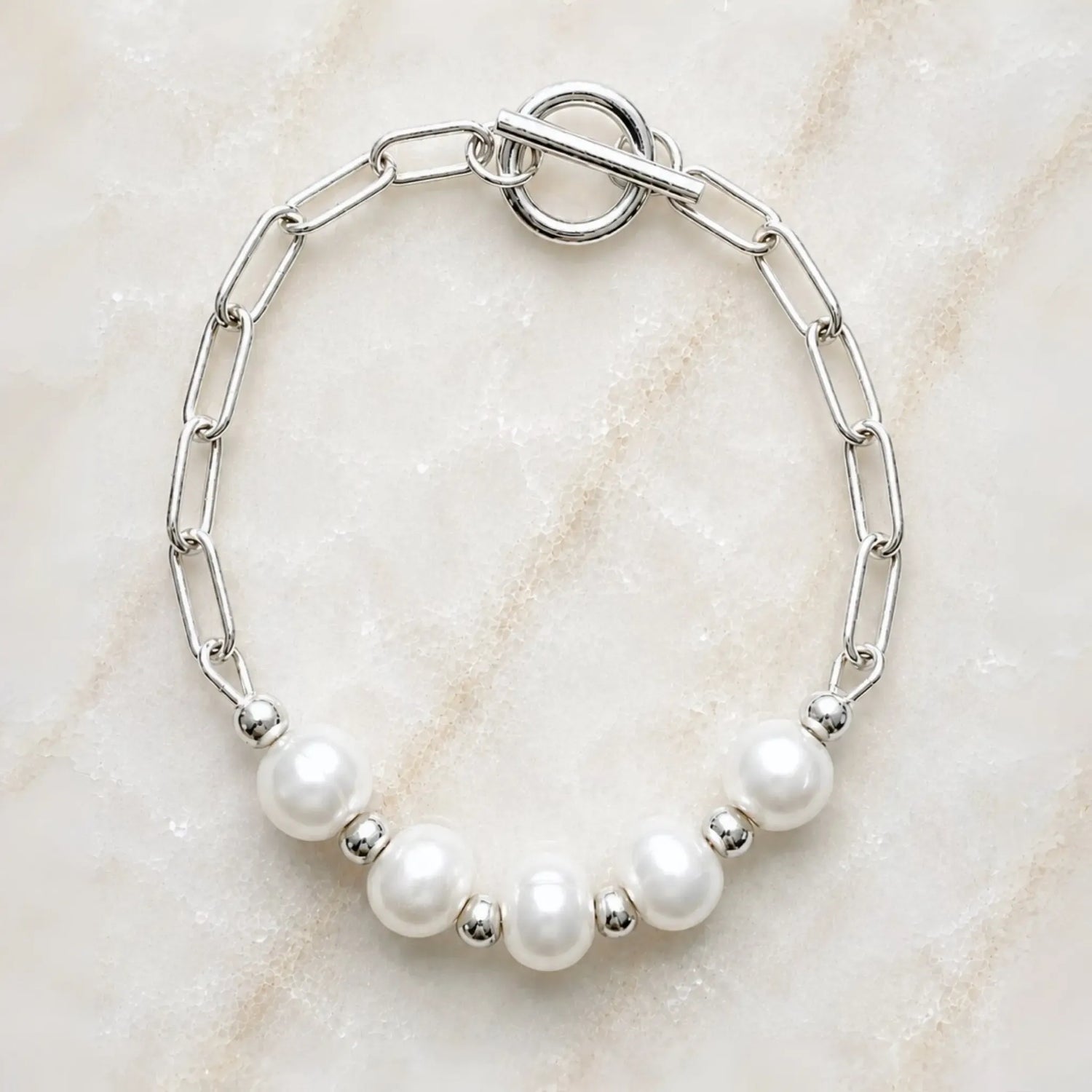 Callie freshwater pearl bracelet handcrafted in Canada with 9–10 mm freshwater pearls, silver paperclip chain and toggle clasp on white quartz background.